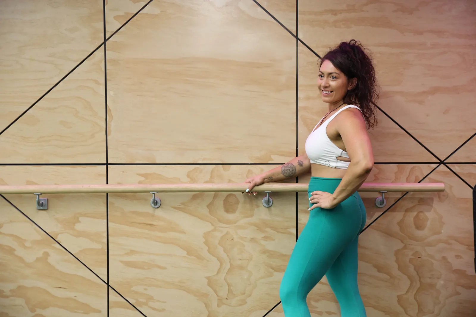 Kiri at a ballet barre against a plywood wall